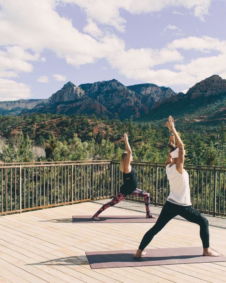 Two women practicing yoga on a sunny deck