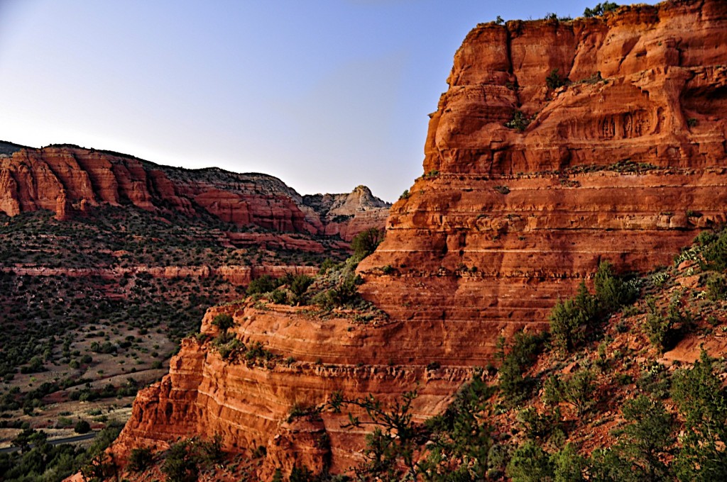 Red cliff mesa with background of tree covered canyon.