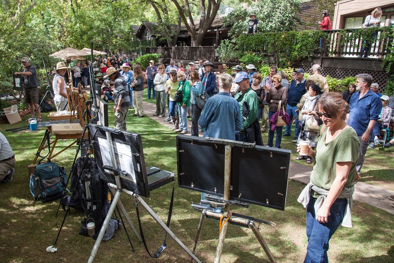 An outdoor art exhibition with people lined up to view