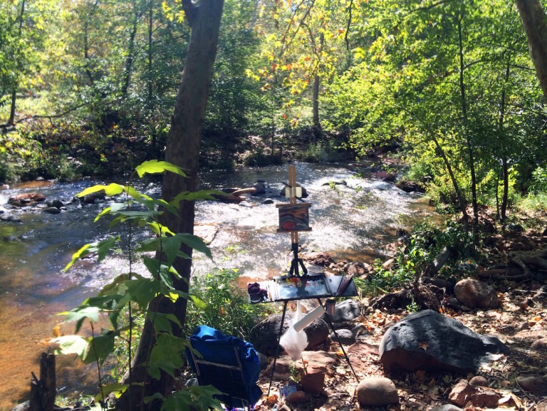 A painter's easel set up by a creek in the forest