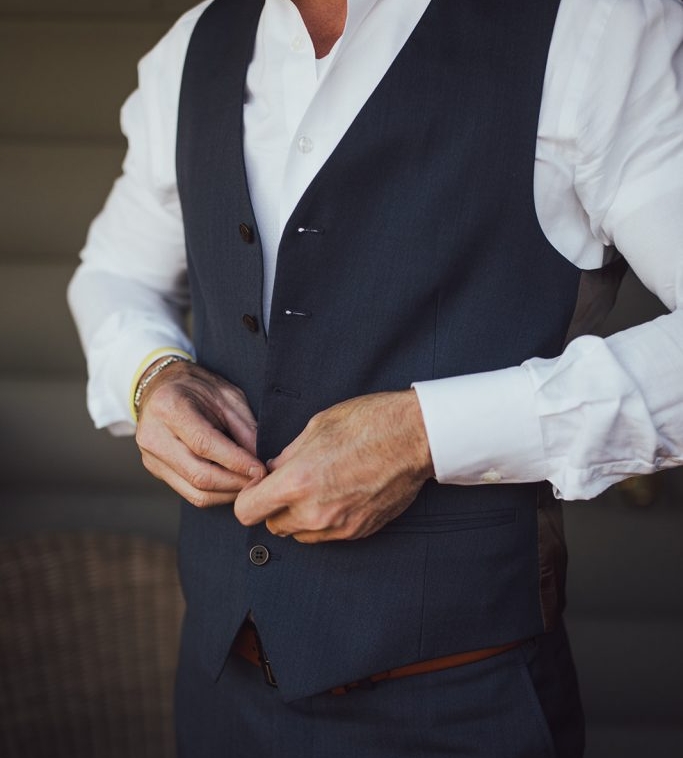 A man buttoning up suit vest
