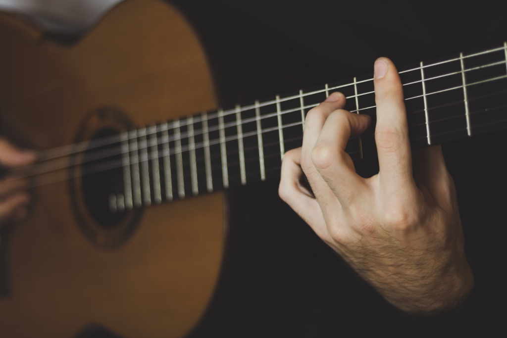 close up of a man playing an acoustic guitar