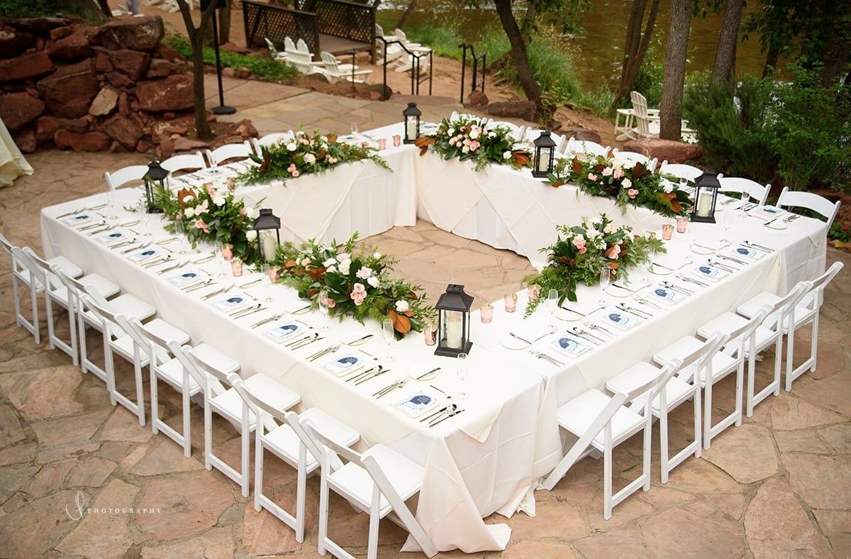 square wedding reception table set for 25 people with lanterns and white linens outside