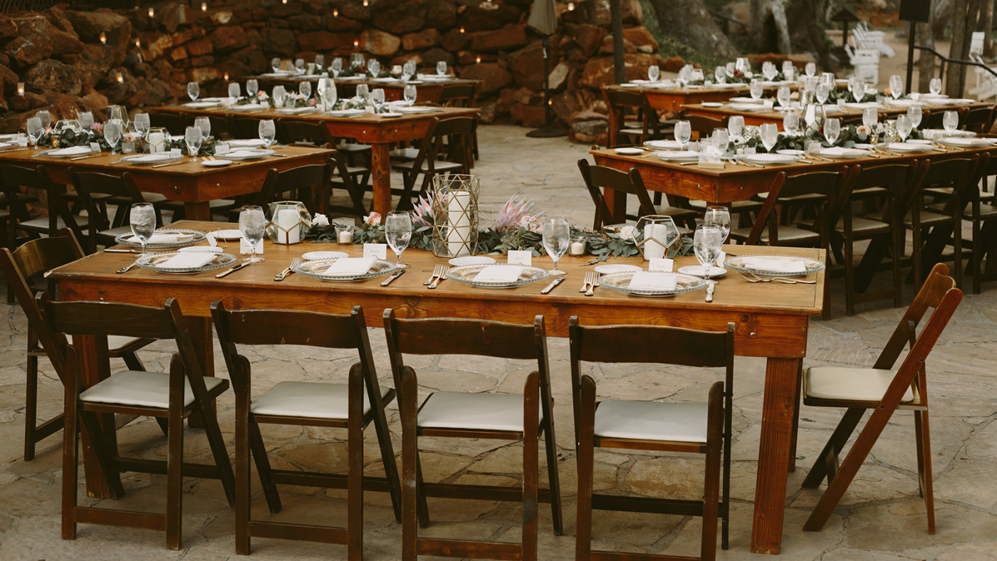 wooden tables set for outdoor wedding reception dinner