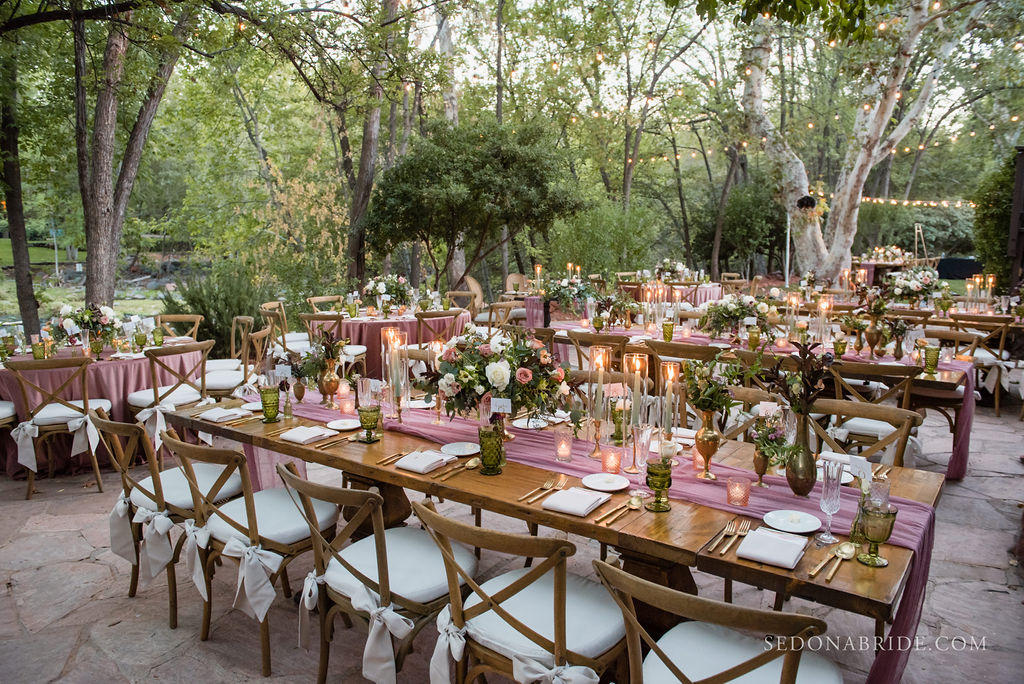wedding reception area set for dinner outside with trees in the background