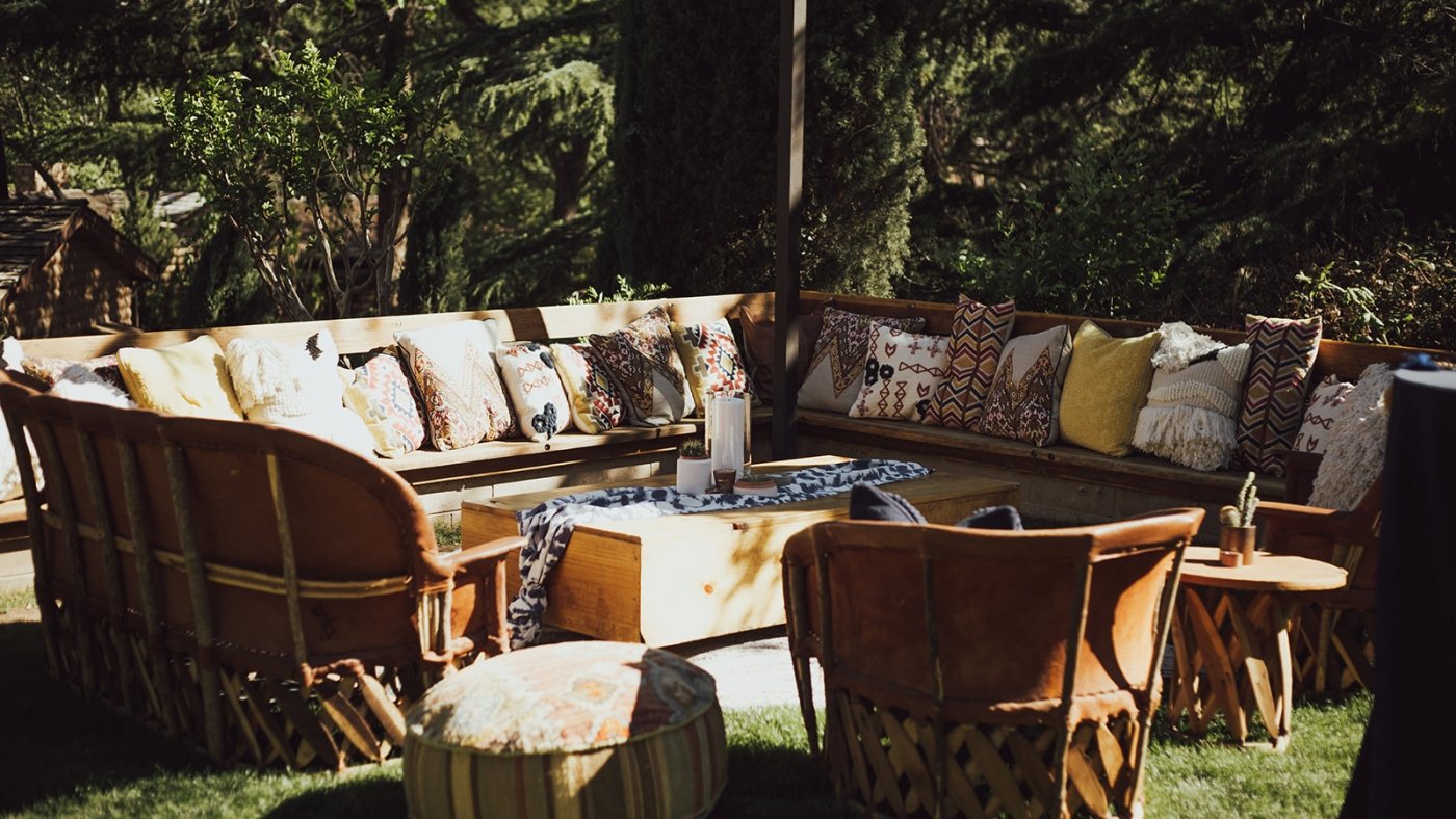 outdoor patio furniture with many cushions and trees in the background