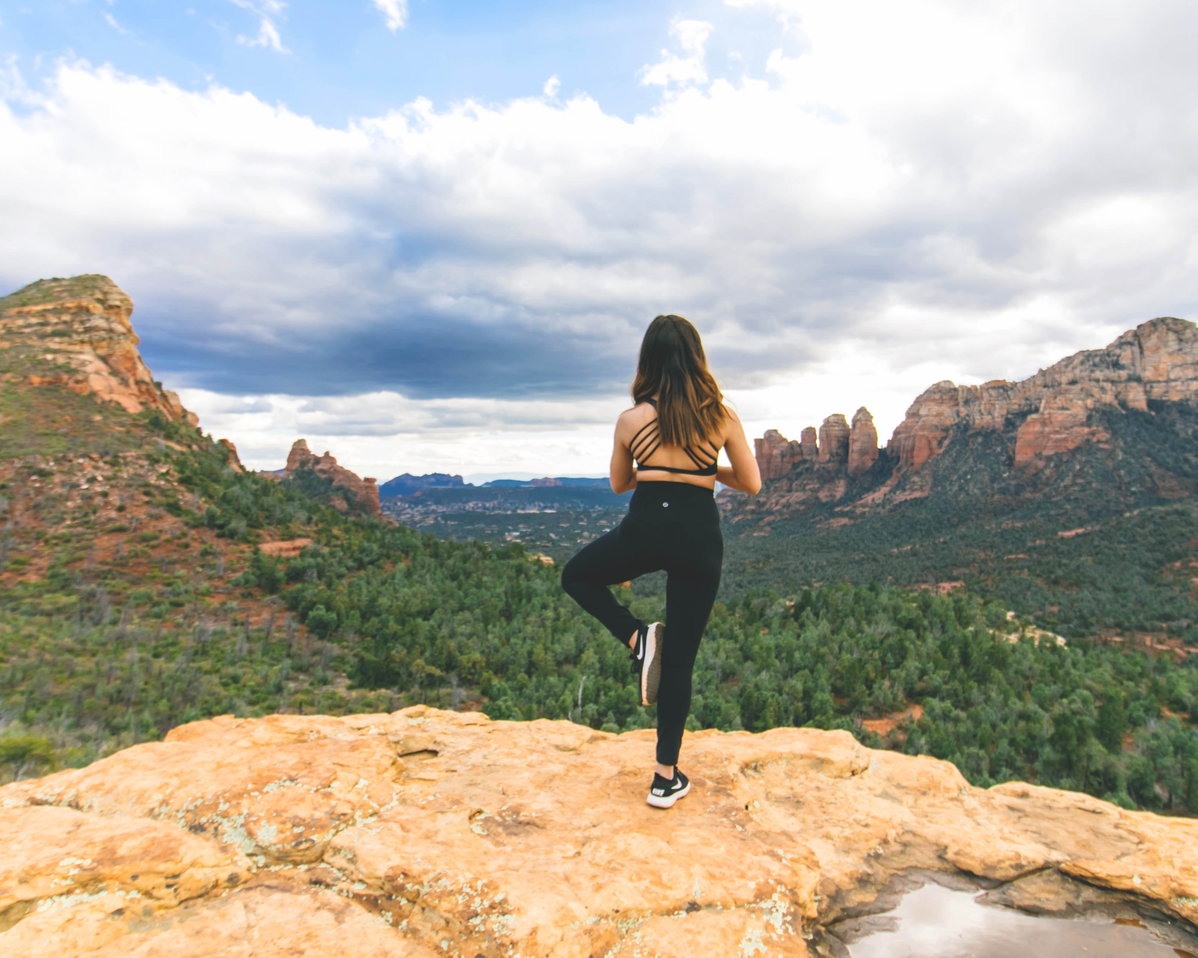 Woman meditating on rock face overlooking Sedona red rocks