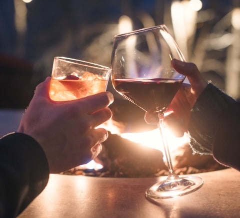 Two people cheersing glasses in front of a fit pit at the Cress Bar