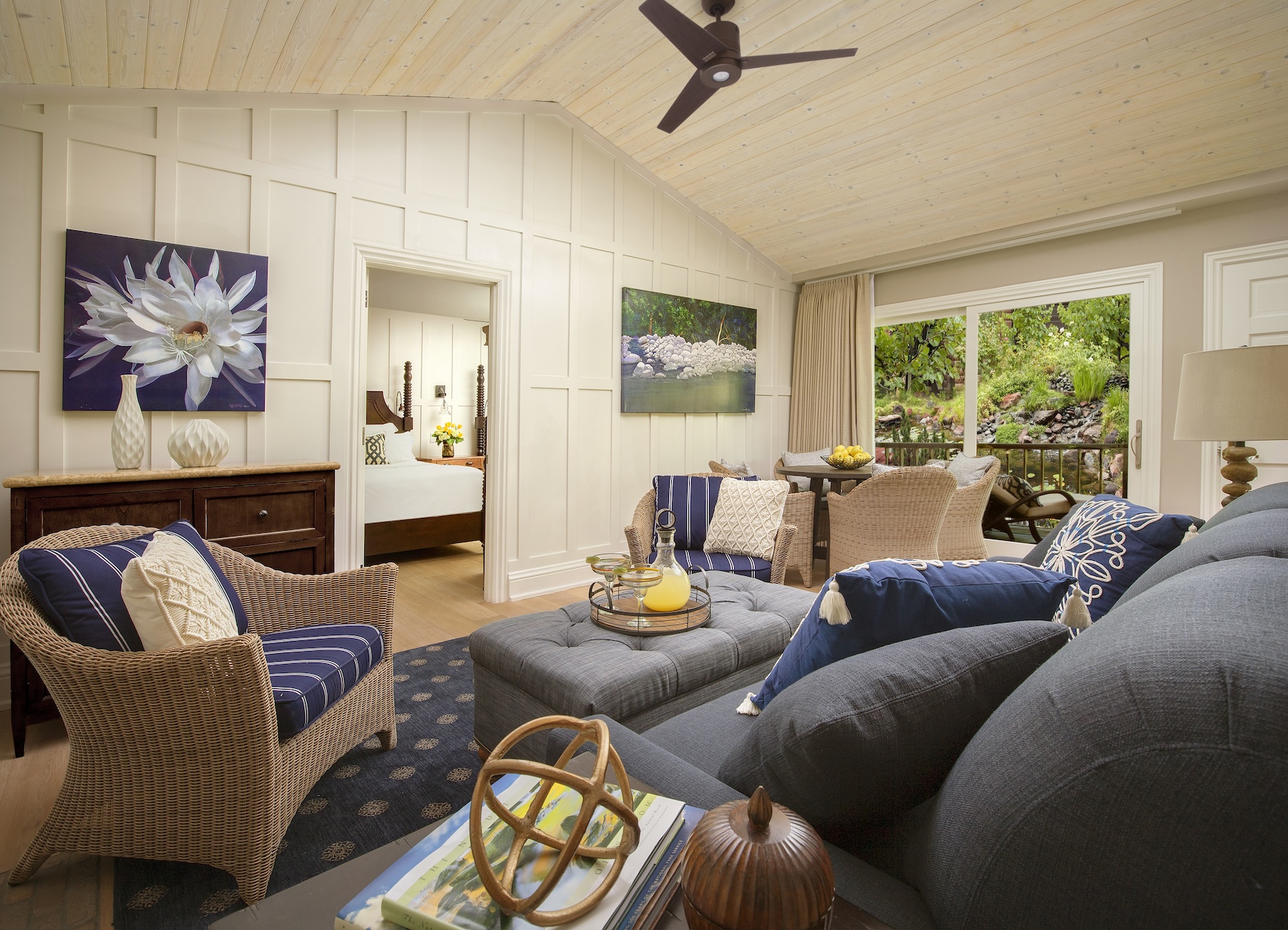 A living room with a gray sofa, wicker chair, and tufted ottoman.