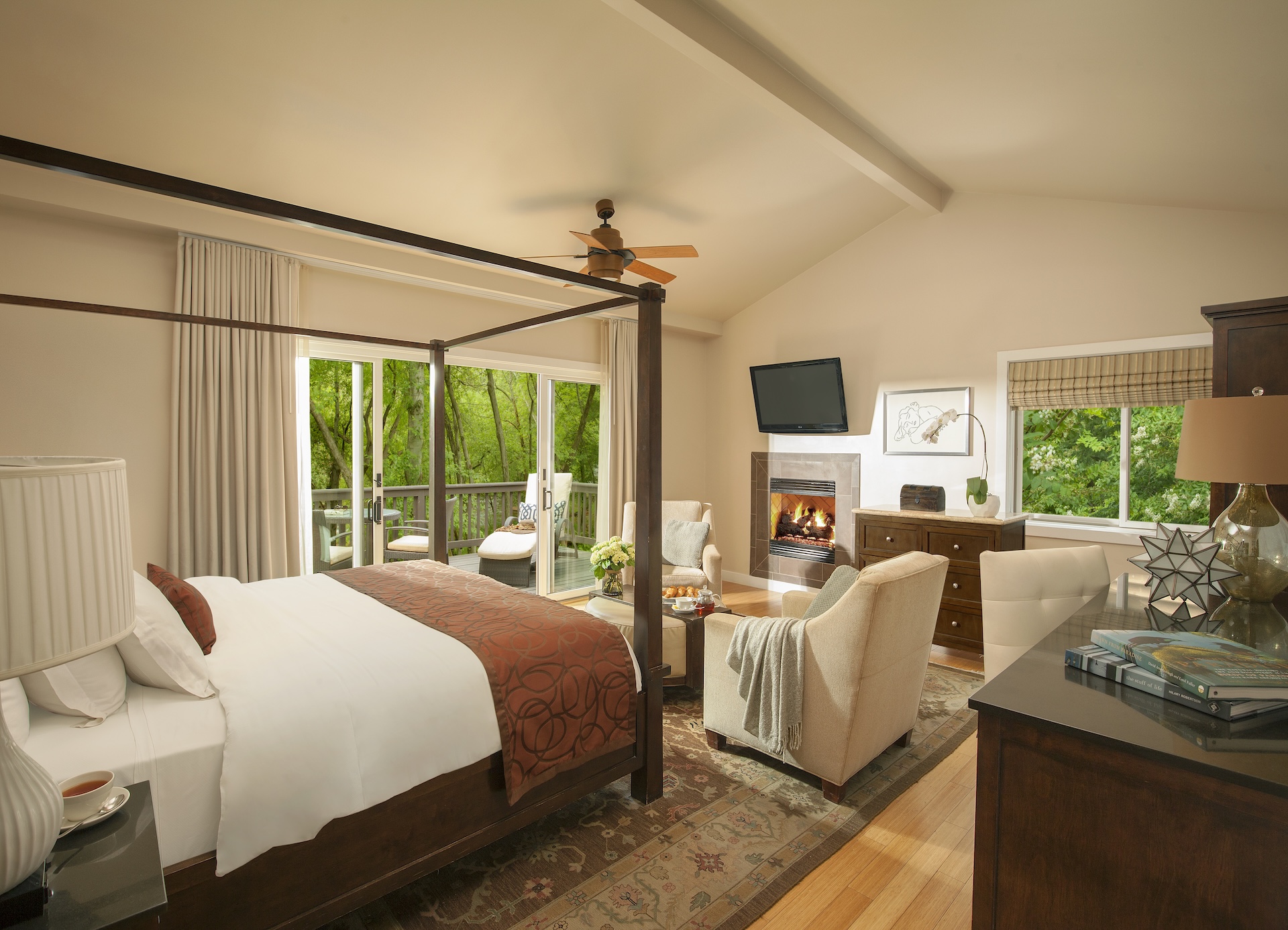 A spacious room with a four-poster bed, fireplace, and seating area.