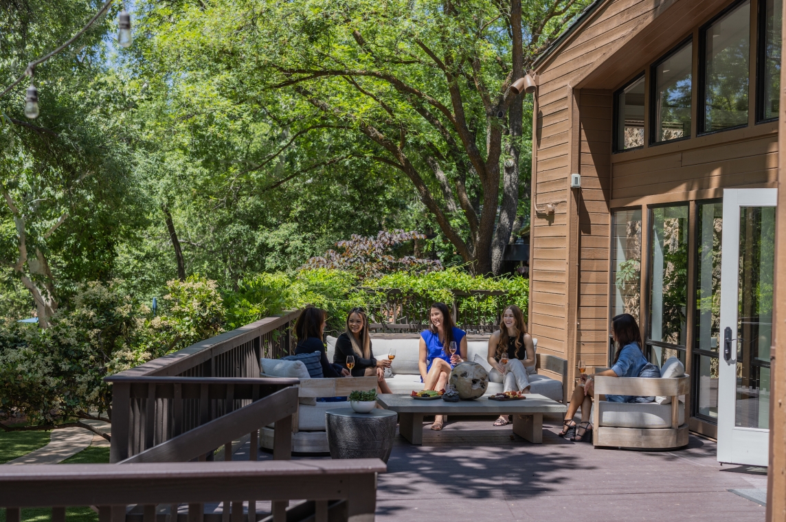A group of people sitting on a deck with outdoor furniture