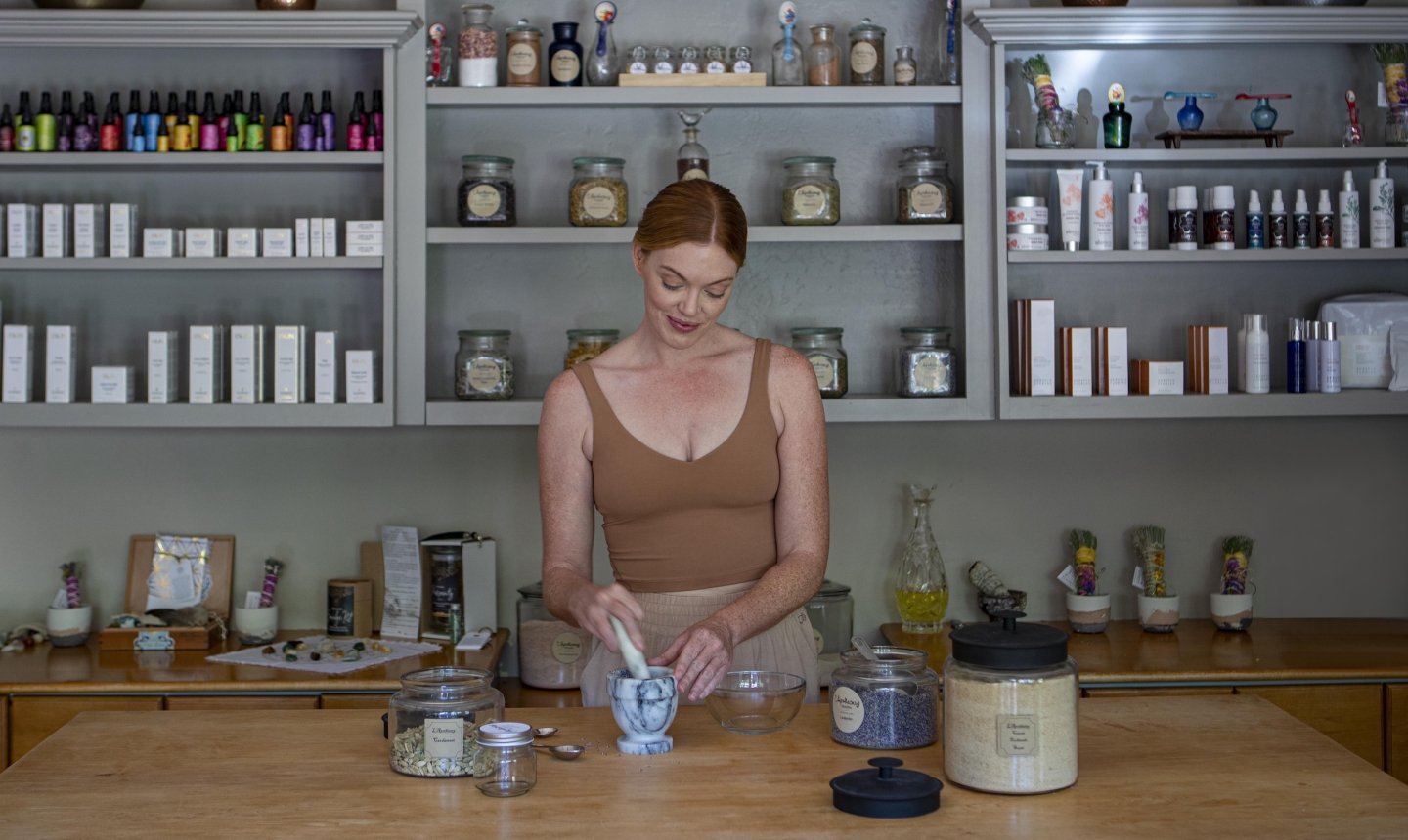 Person using a mortar and pestle to blend herbs at L'Apothecary spa
