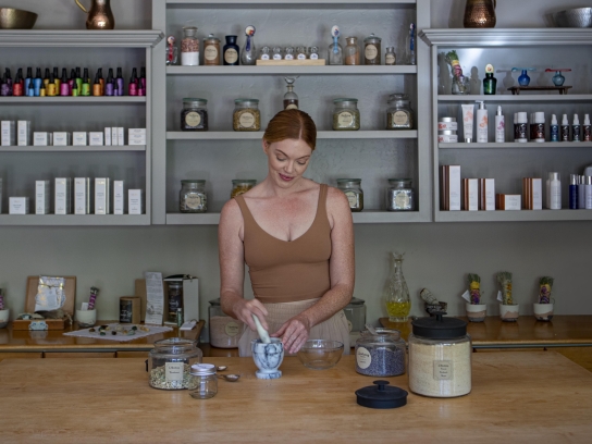 Person using a mortar and pestle to blend herbs at L'Apothecary spa
