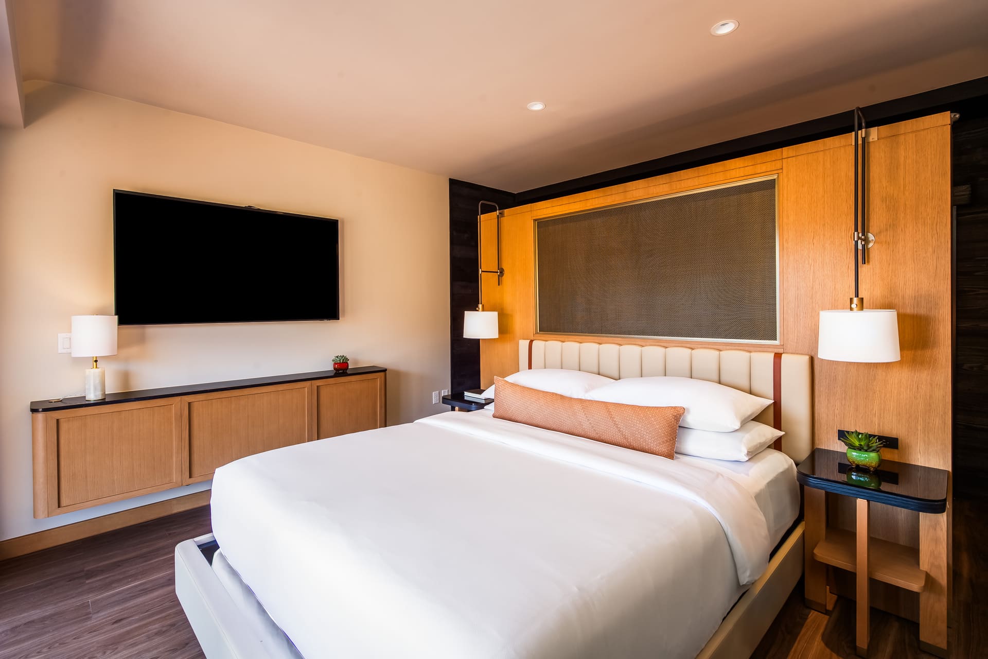 A hotel room with a large bed, TV, and modern furnishings