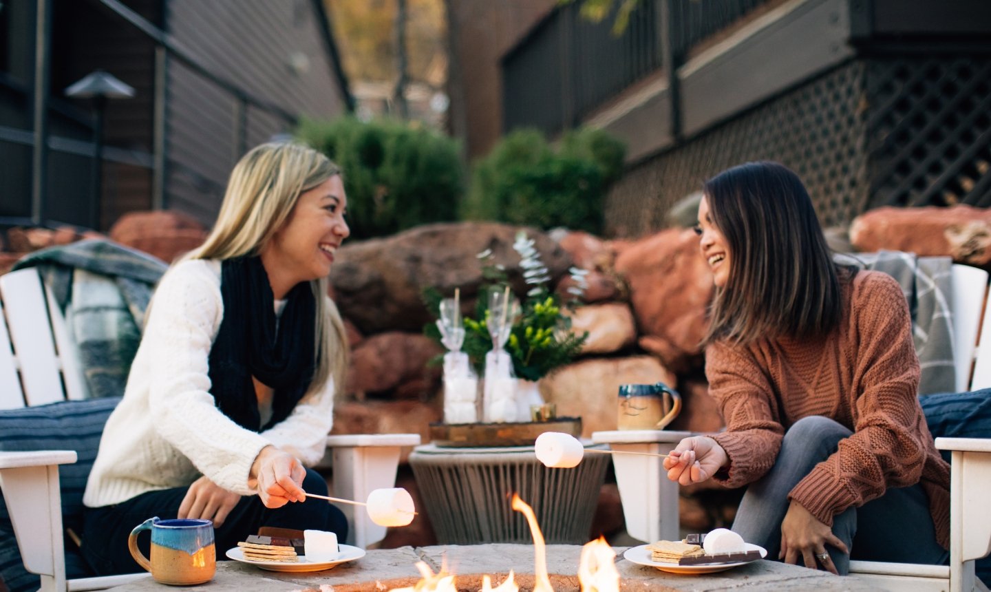 Two women around fireplace with s'mores