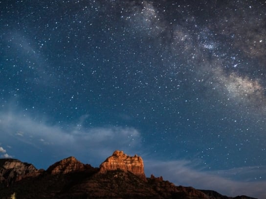 A stunning night sky filled with the Milky Way and countless stars, glowing above Sedona's red rock formations.