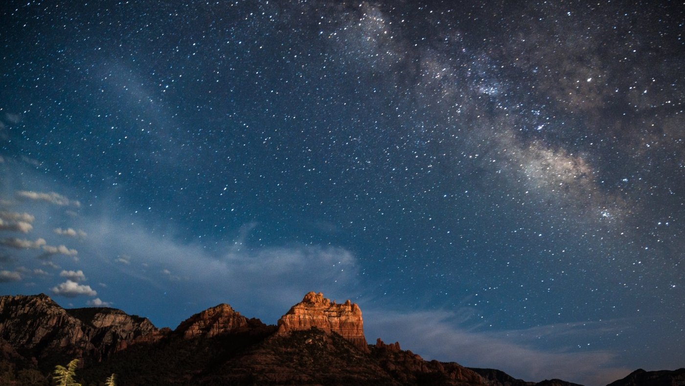 A stunning night sky filled with the Milky Way and countless stars, glowing above Sedona's red rock formations.