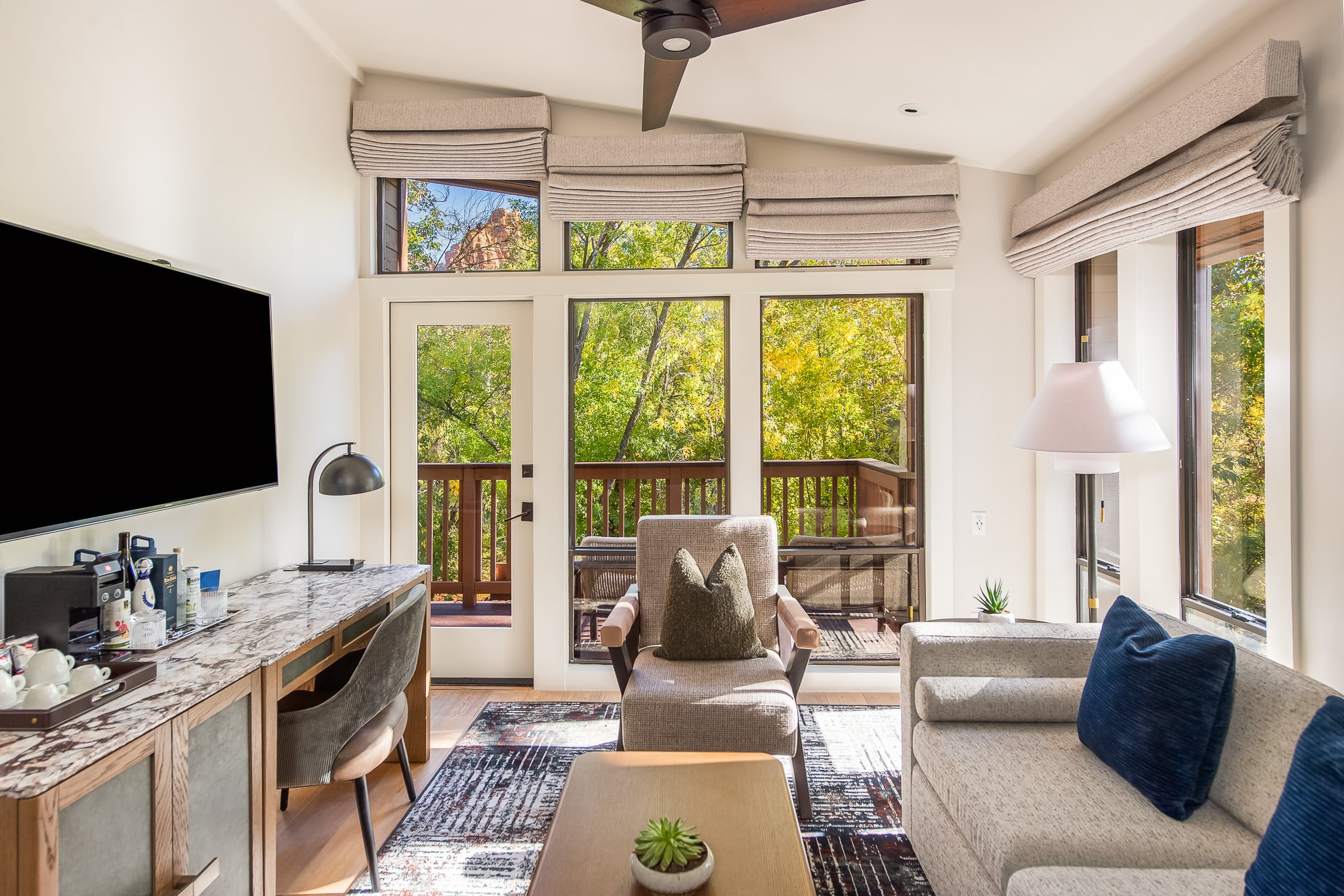 A bright and airy living room with a desk, sofa, and TV