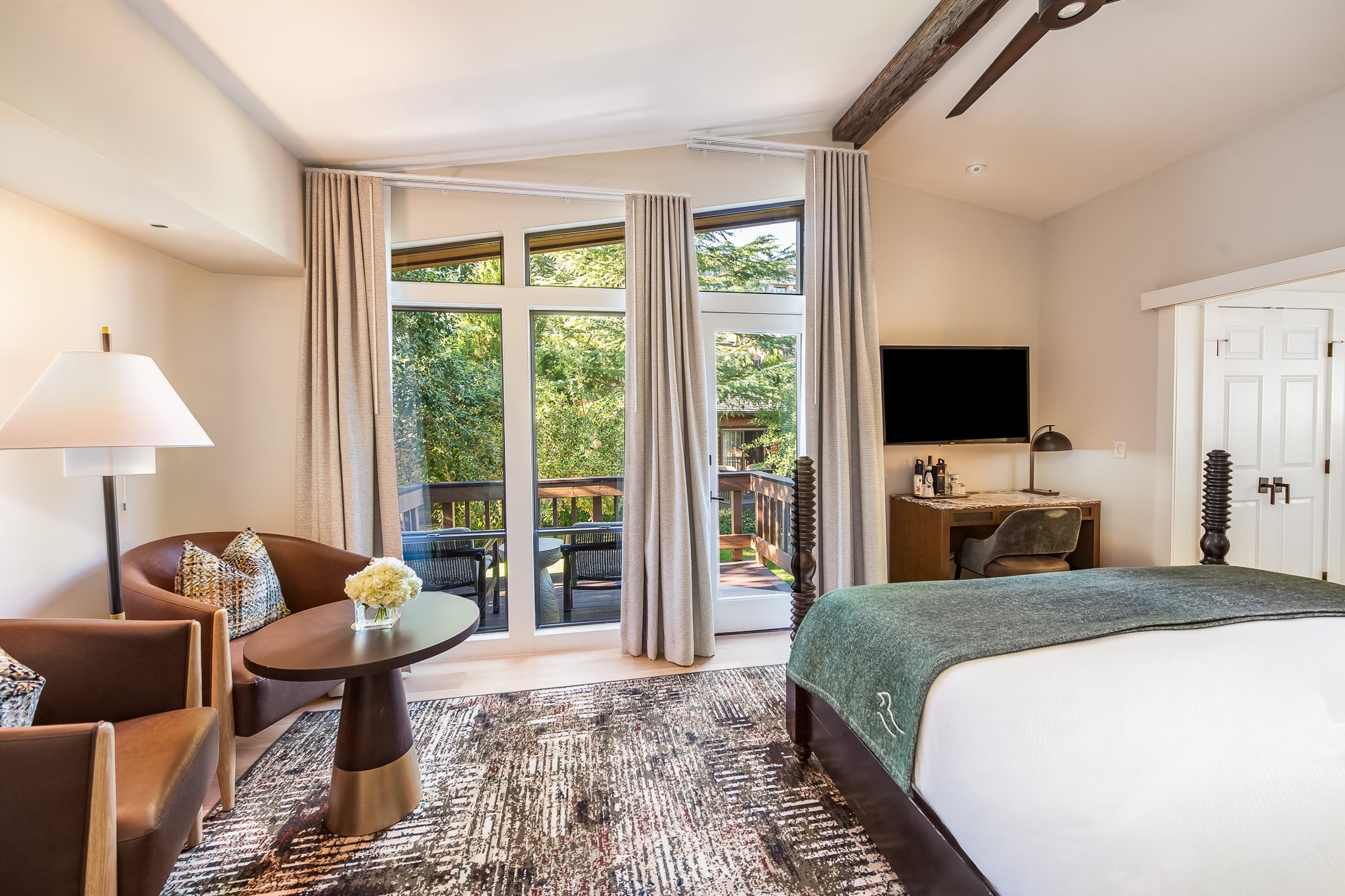 A hotel room with a king-size bed, sitting area, desk, and balcony access.