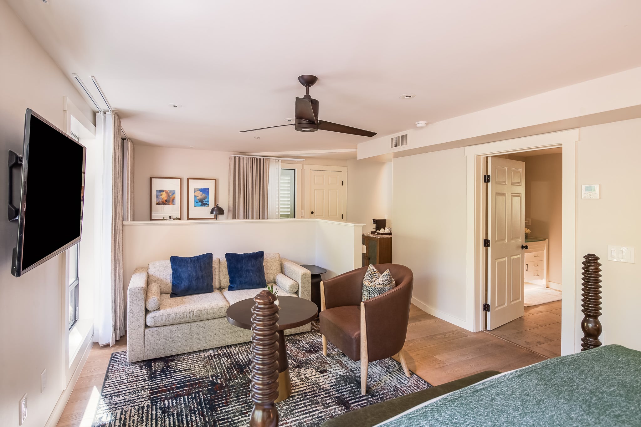 A hotel room with a sofa, chair, coffee table, and TV