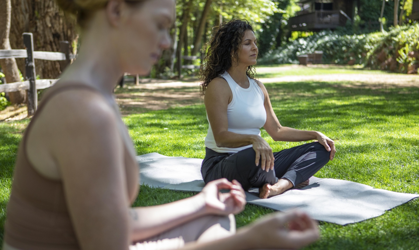 Two women yoga on lawn