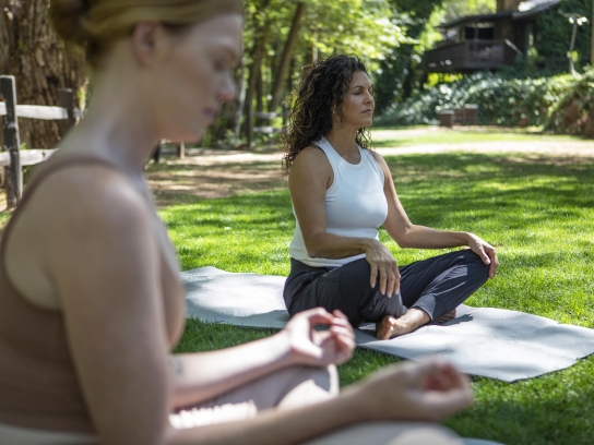 Two women yoga on lawn
