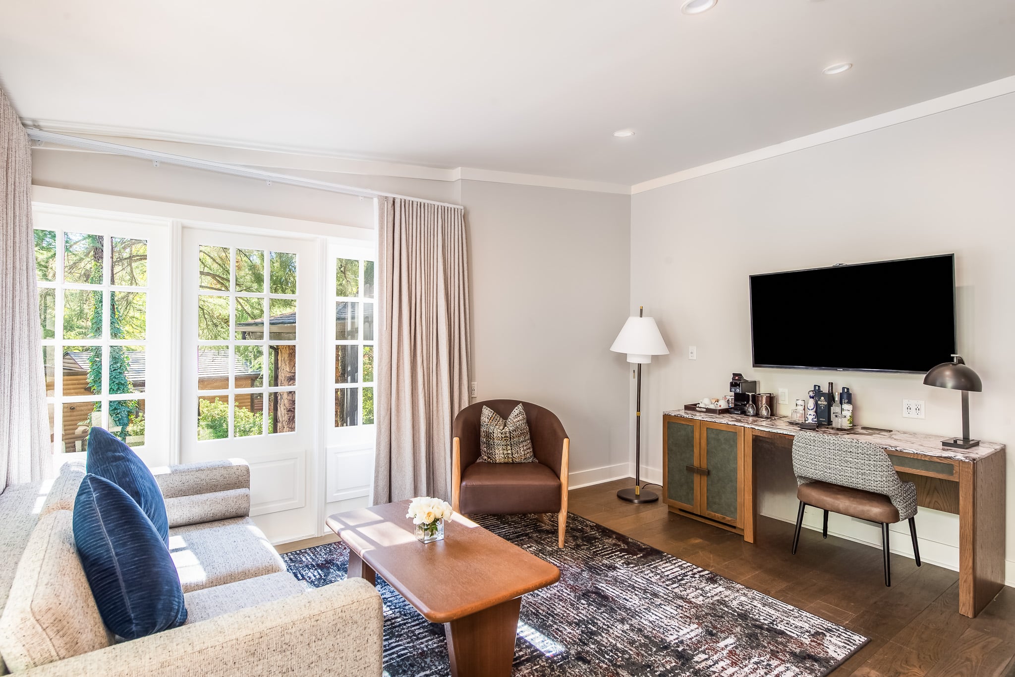 A wide view of a junior suite with a sofa, desk, TV, and coffee table.