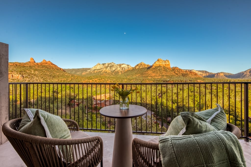 A private balcony with two chairs and a table, offering a stunning panoramic view of Sedona's red rocks.