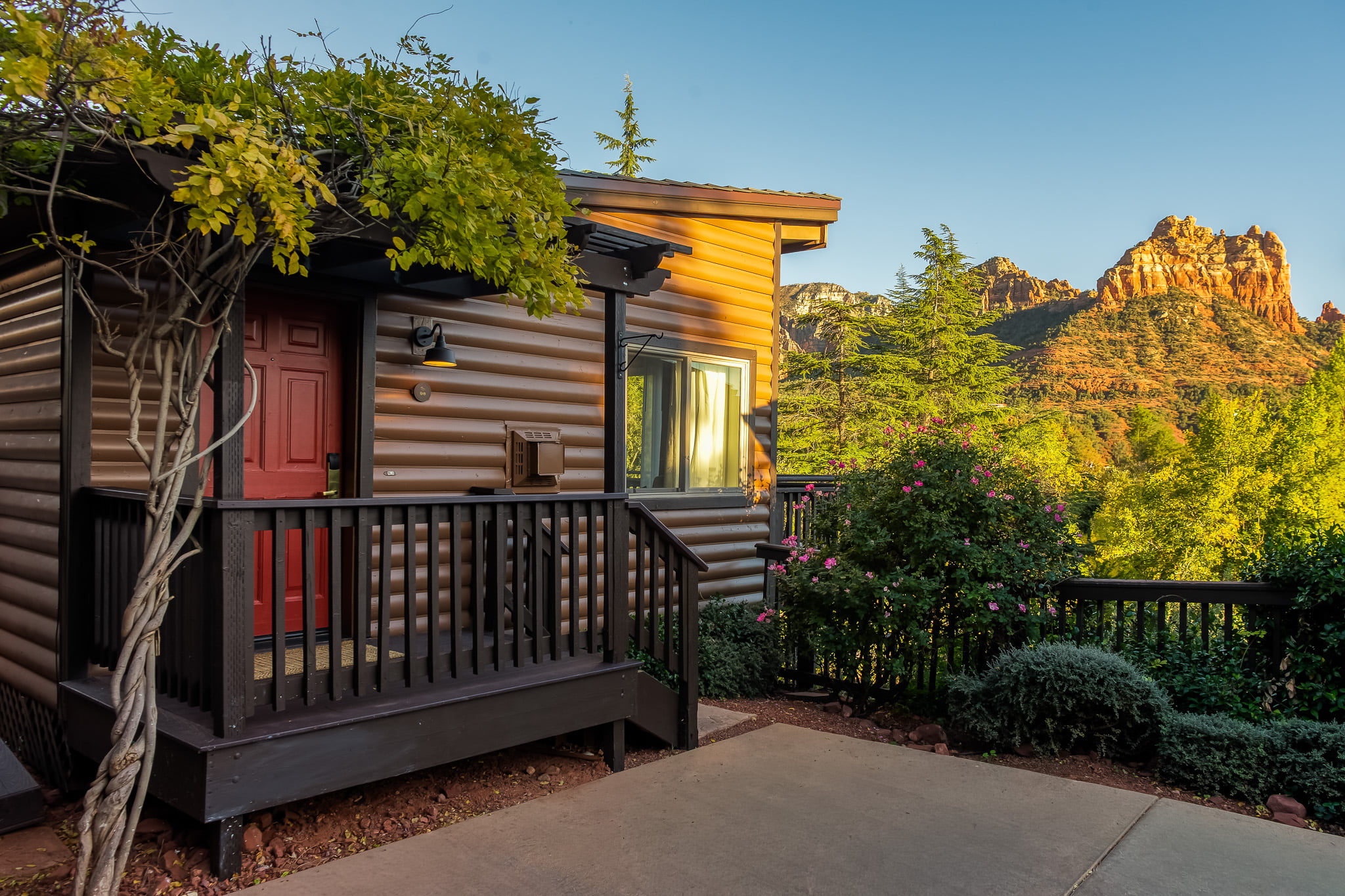 A log cabin-style building with a red door and a porch overlooking a mountain view.