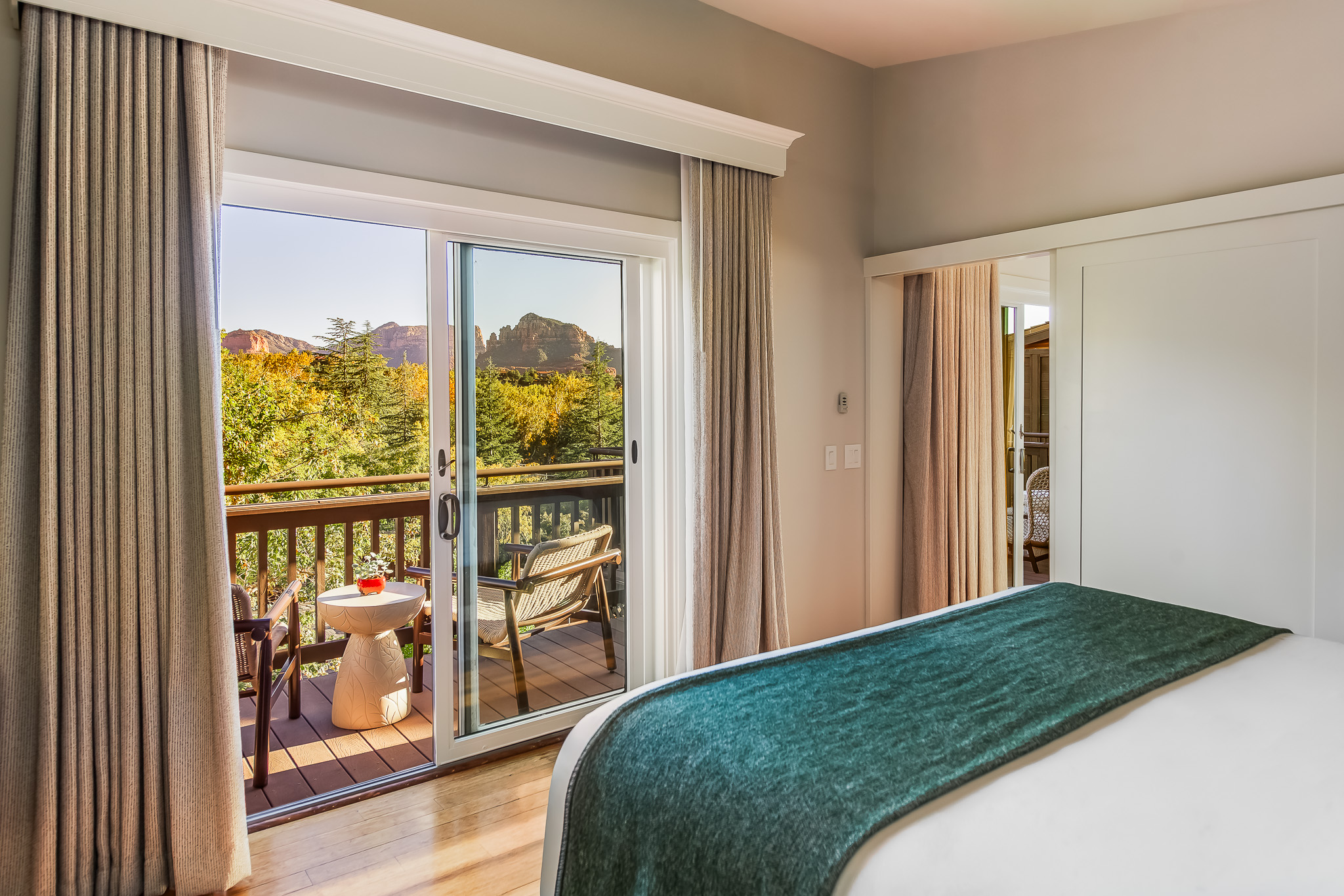 A hotel room with a bed, sliding glass door, and balcony overlooking mountains.